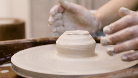 close up view of hands of a clerk modeling ceramic piece on a potter wheel in a workshop 1 1