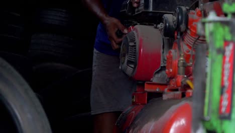 Slow-motion---A-man-starting-air-compressor-belt-driven-machine-manually-on-workshop