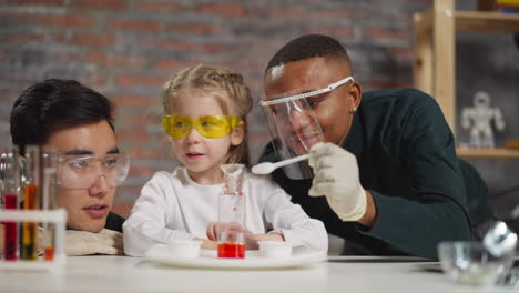 little girl student adjusts funnel and stirs material in lab