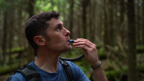 a backpacker sips water from his hydration pack