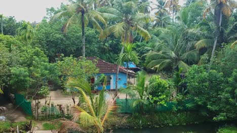 Aerial-view-of-a-beautiful-little-house-standing-by-the-shore-of-the-lake-,-Rural-house-in-India-,-Aerial-view-of-a-small-house