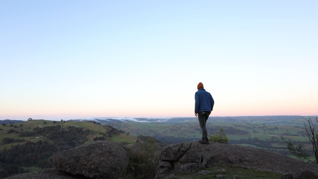구름이 구름을 타고 빅토리아의 고지대 풍경을 따라 이른 아침 햇살에 망루에 있는 남자