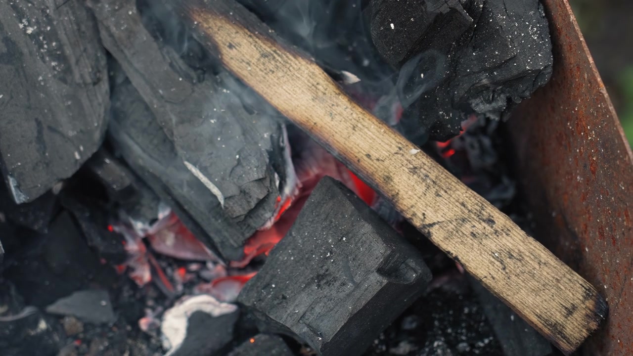 Rozżarzone węgle i drewno palące się w metalowym palenisku