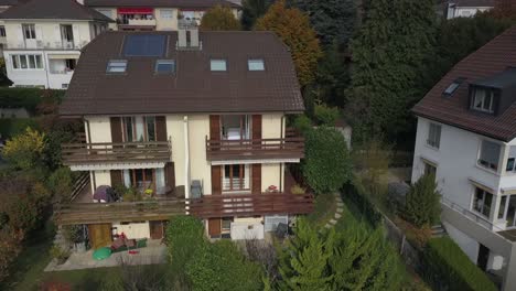 Vista-Aérea-De-Expulsión-De-Drones:-El-Drone-Vuela-Hacia-Arriba-Y-Lejos-De-Una-Casa,-Una-Villa-En-Suiza-Y-Revela-Las-Casas,-El-Jardín-Y-Los-árboles-De-Los-Alrededores,-Vaud