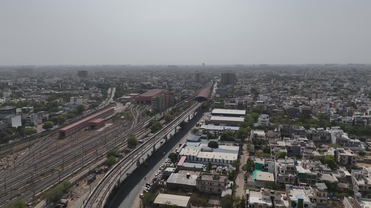 Overhead perspective of Jaipur's dense cityscape with railway tracks and metro train station