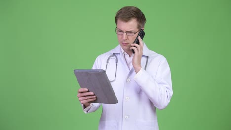 man doctor using digital tablet while talking on mobile phone