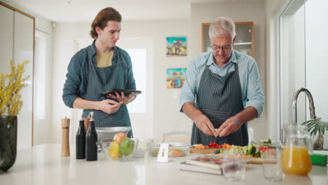 father and son cooking salad in the kitchen