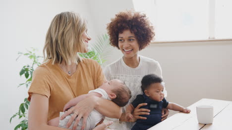 two mothers with babies meeting around table on play date at home