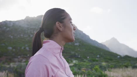 mujer de raza mixta ejercitando el descanso durante una carrera en el campo por una montaña