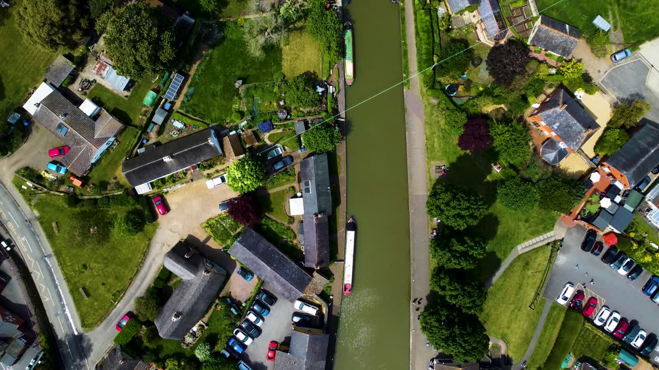 High aerial bird's eye view pan along peaceful canal in stoke bruerne