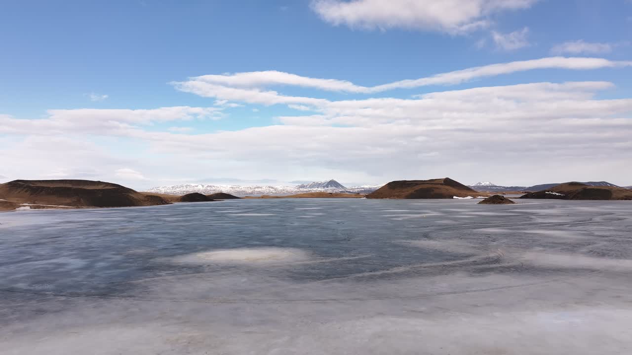 Frozen Lake Mývatn surrounded by volcanic pseudocraters under a blue sky in Skútustaðir, Iceland.