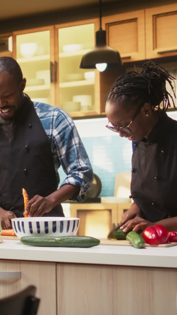 Video verticale: coppia felice che taglia verdure fresche su un tagliere in cucina