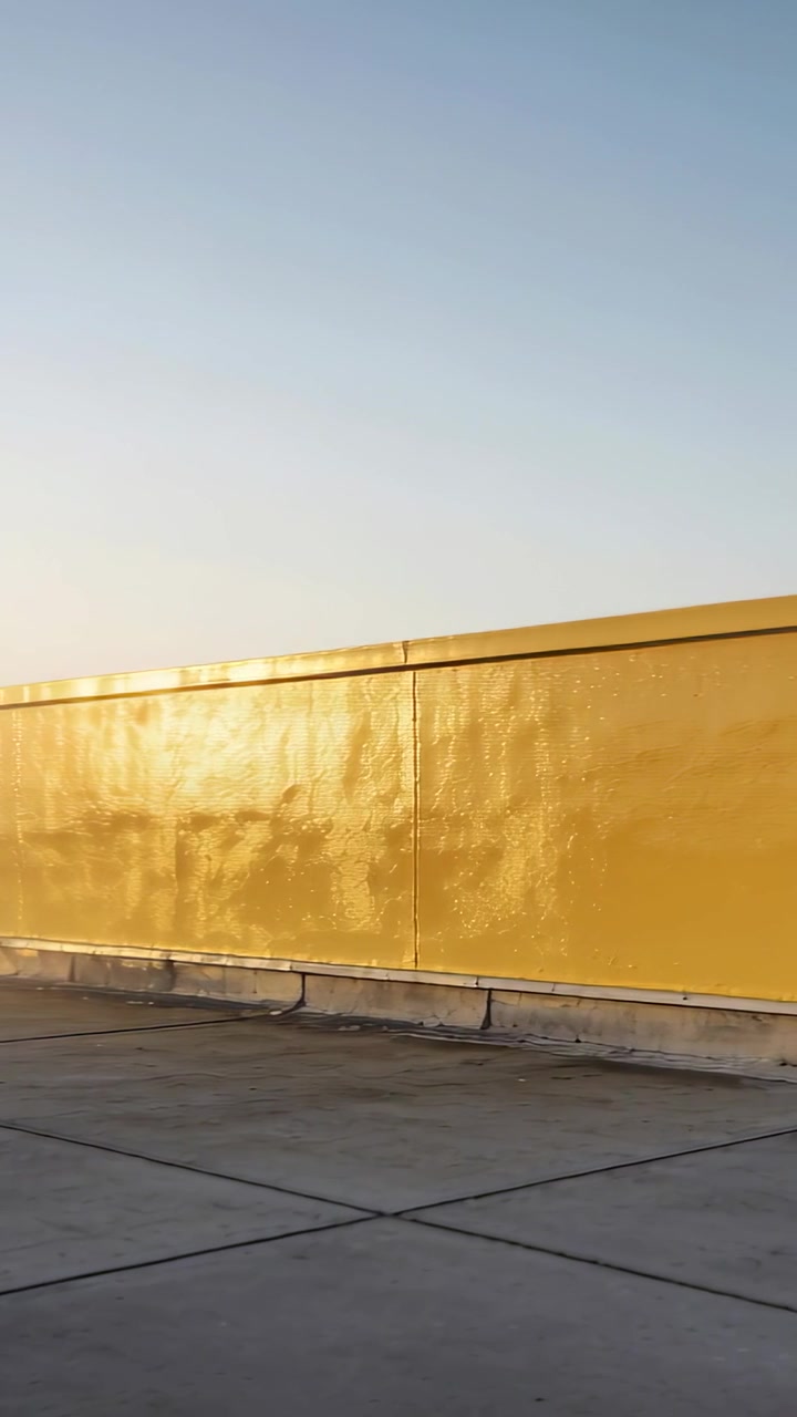 Video vertical: Cámara iniciando un paneo en una azotea, revelando un pretil amarillo y juntas, mostrando un destello