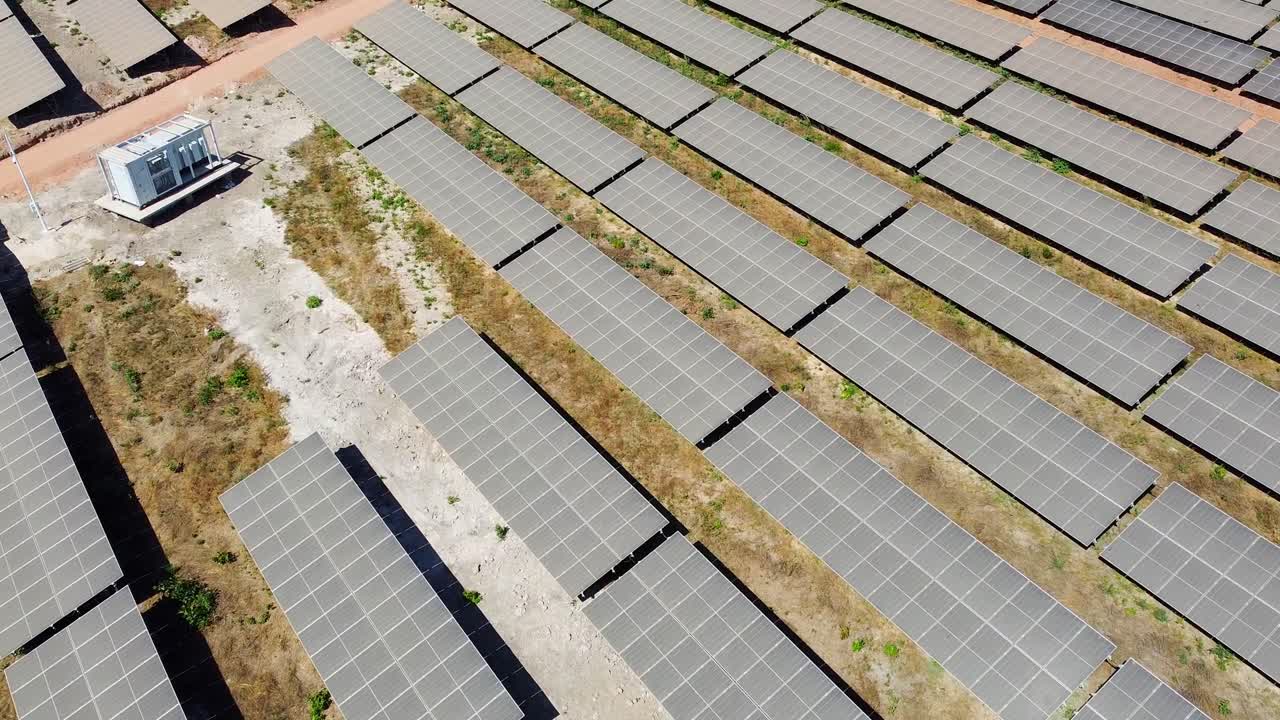 Aerial high bird's eye overview plus tilt up of inverters and very contrasting dirty and clean PV panel modules