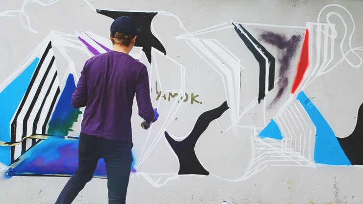 L'artista disegna graffiti su una recinzione. Disegno astratto. L'artista disegna graffiti su una recinzione