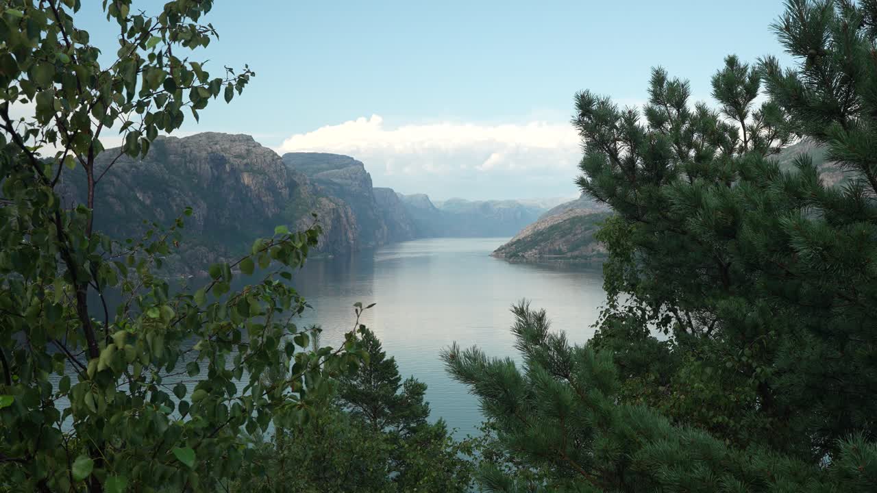 En lugn fjord speglar de omgivande bergen under en mjuk skymningshimmel. Frodig grönska ramar in scenen och förstärker den fridfulla atmosfären i detta fantastiska norska landskap.