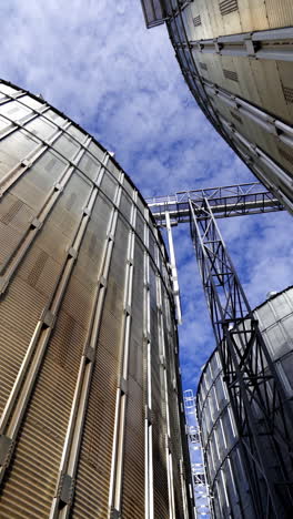 granary grain elevators. metal tanks for the storage crop. large bins for farming. aluminum containers against blue sky. close-up. vertical video