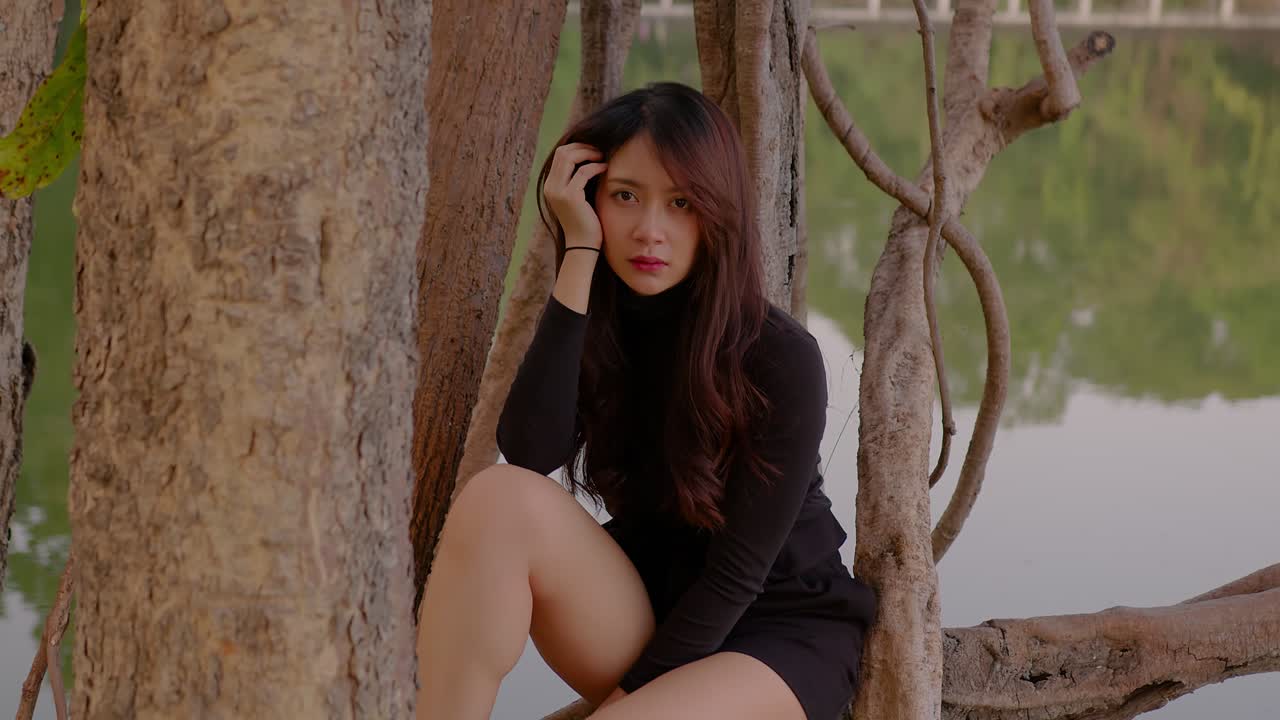 Woman Sitting Among Trees by a Lake