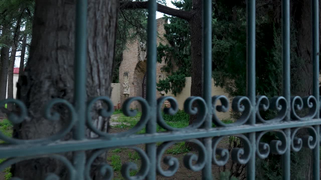 Dekorativt hegn i en have med udsigt til historisk bygning