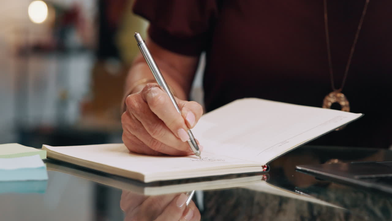 Close-up of a Hand Writing in a Notebook with a Pen