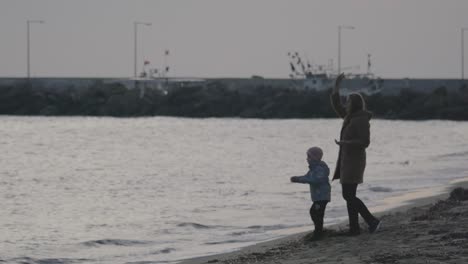 in nea kallikratia greece on sea coast a young mother with a small son throwing small rocks into water