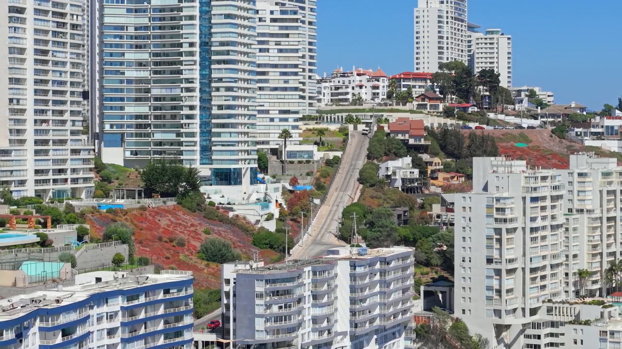 Una vista aerea teleobiettivo di moderni edifici residenziali a Concón, Cile, in una giornata di sole, con auto che percorrono le colline