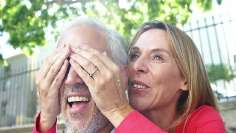 mujer madura está escondiendo los ojos de su marido en la calle