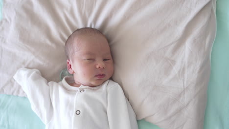 cute baby is slowly falling asleep. he blinks his eyes and smiles a little. sleepy sweet child look from above.