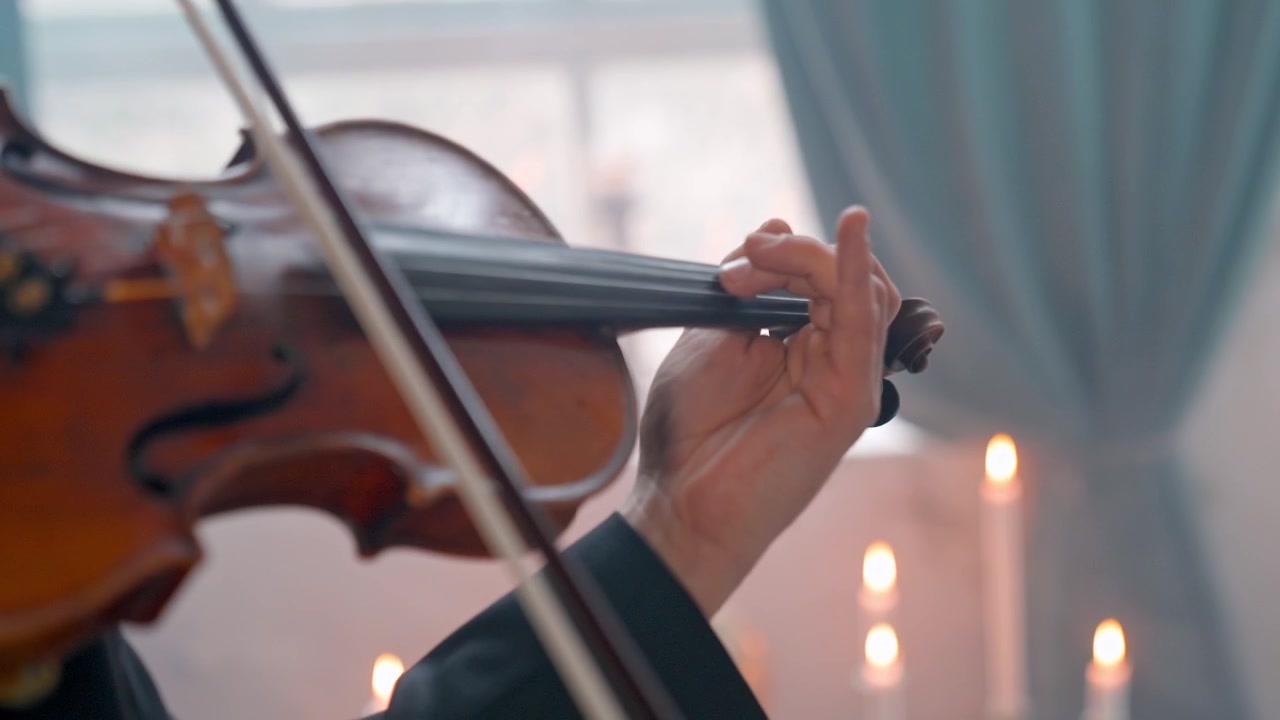 Primo piano di un musicista che suona il violino con luci bokeh sullo sfondo