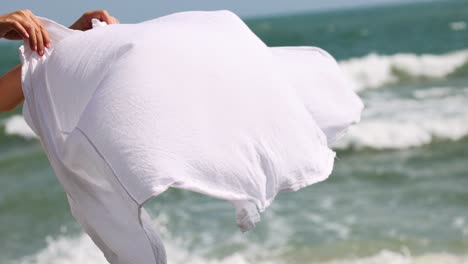 flowing white fabric twirls against ocean backdrop