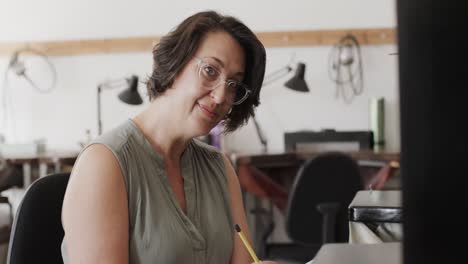 Portrait-of-happy-caucasian-female-worker-with-glasses-writing-in-jewellery-studio-in-slow-motion