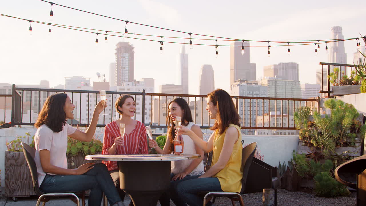 amigas haciendo un brindis para celebrar en la terraza del techo con el horizonte de la ciudad en el fondo