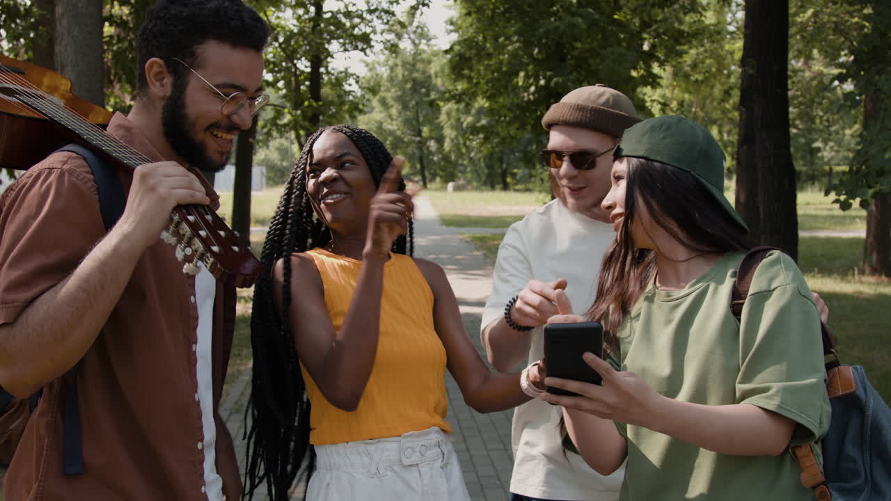 Diverse group of friends interacting with a smartphone in a park