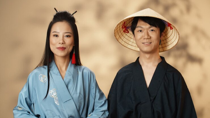 Asian young couple in traditional Chinese costumes smiling at camera