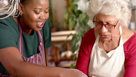 Happy-diverse-female-potters-using-potter's-wheel-in-pottery-studio,-slow-motion