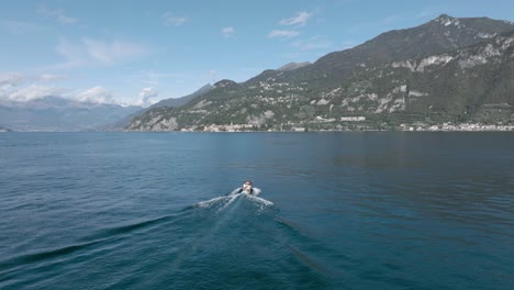 4k aerial - following medium shot behind a classic boat in lake como, italy