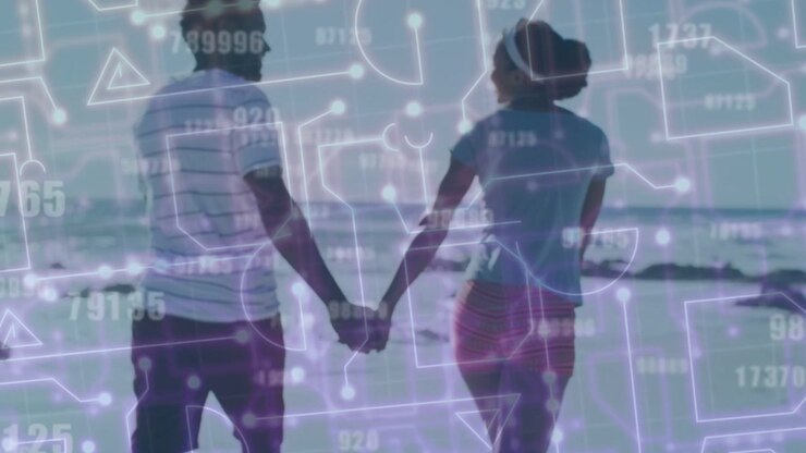 Couple holding hands on shoreline toward horizon, pullback revealing digital tech overlaying