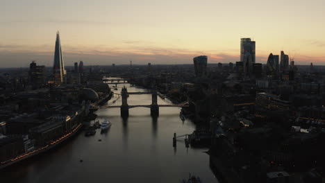 Vista-Aérea-De-Londres,-El-Río-Támesis-Y-El-Puente-De-La-Torre-Justo-Después-De-Que-El-Sol-Se-Haya-Puesto-Y-El-Cielo-Esté-Iluminado