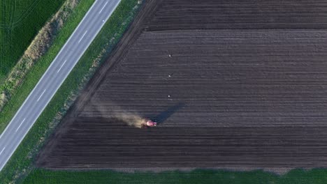 agricultural tractor working on farmland, plowing field in spring, aerial shot