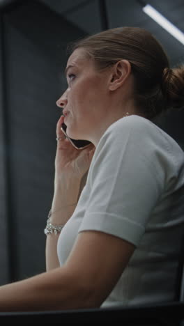 female financial analyst talking on phone, suffering from financial crisis, analyzing exchange market charts on computer and tablet. businesswoman angry about stock market collapse. vertical shot.