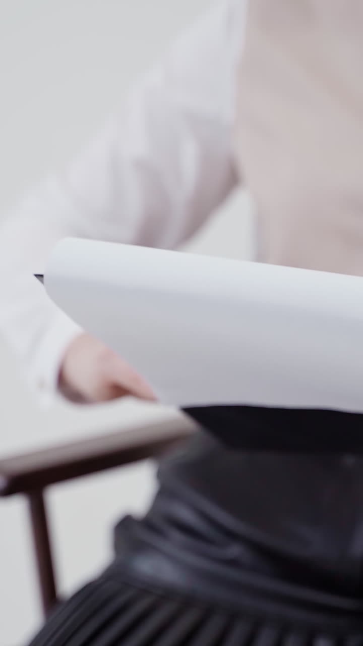 Folder with papers in woman's hands. Young businesswoman sitting in chair and holding documents. Close-up. Slow motion. Vertical video