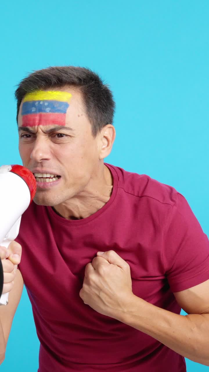 Uomo entusiasta con la bandiera venezuelana dipinta sul viso che usa un megafono