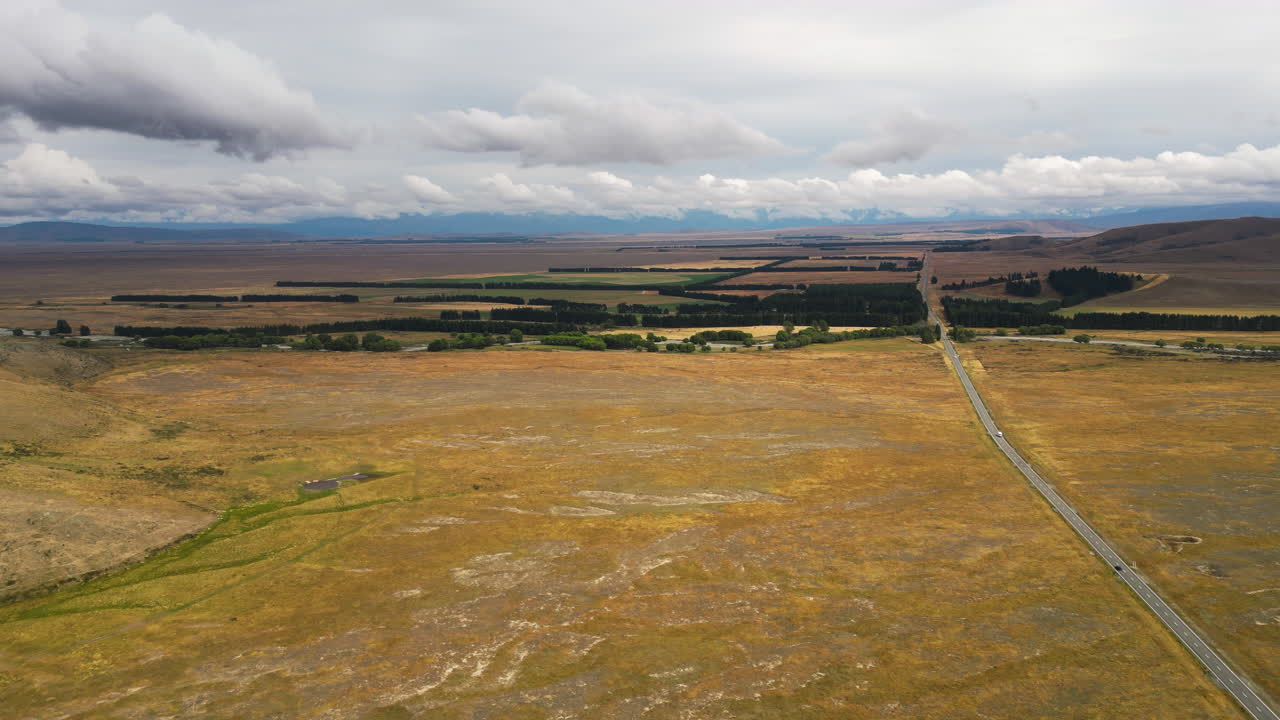 majestuosa vasta llanura atravesada por la carretera del lago tekapo, nueva zelanda, panorama aéreo