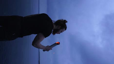 - hombre europeo vertical soplando una antorcha contra un cielo nublado al atardecer