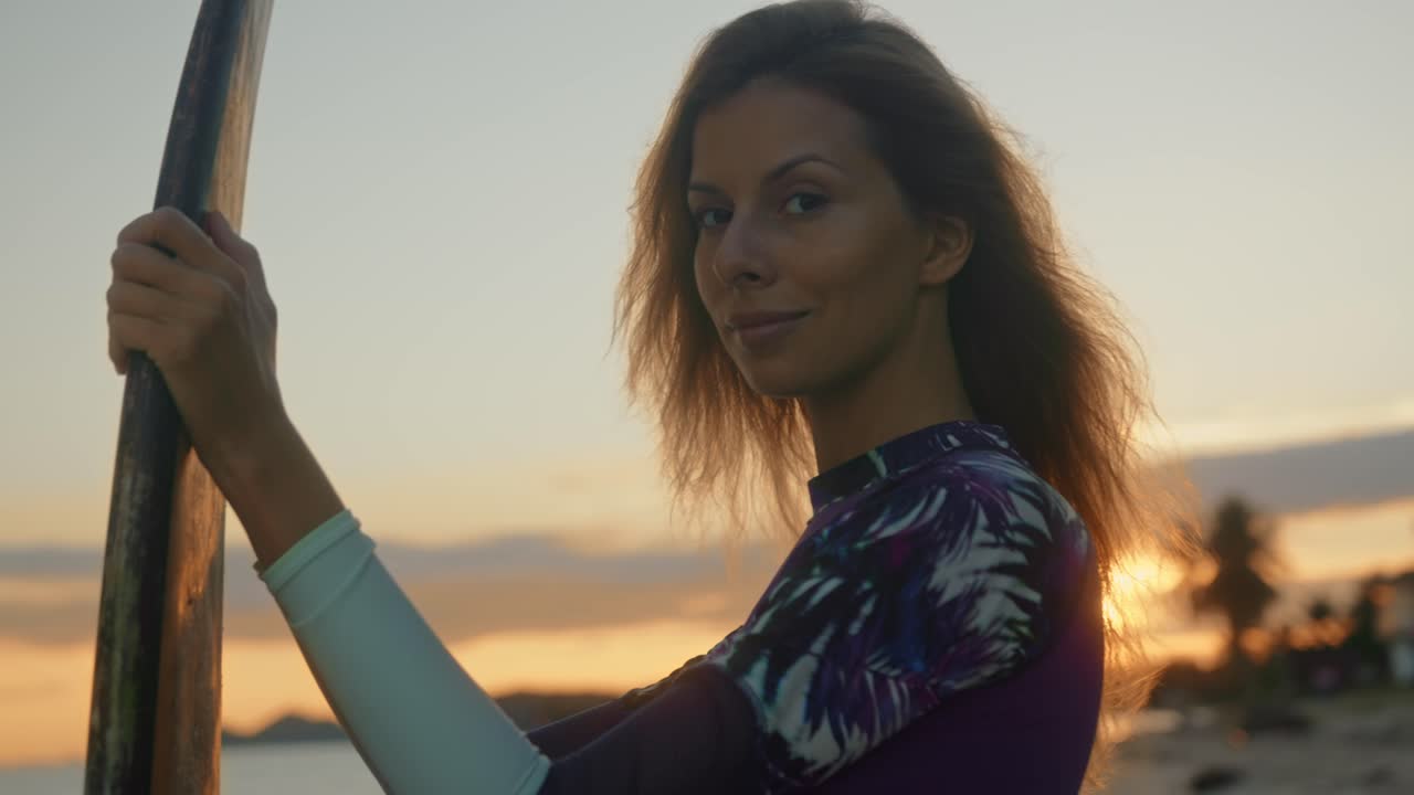 mujer con tabla de surf al atardecer