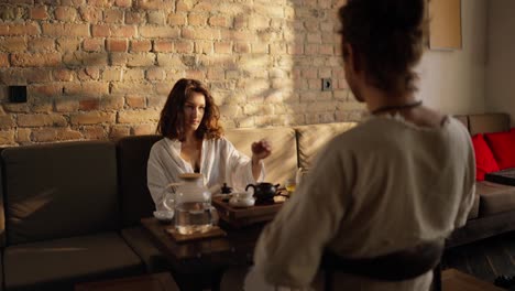 couple sitting on a couch and talking over tea