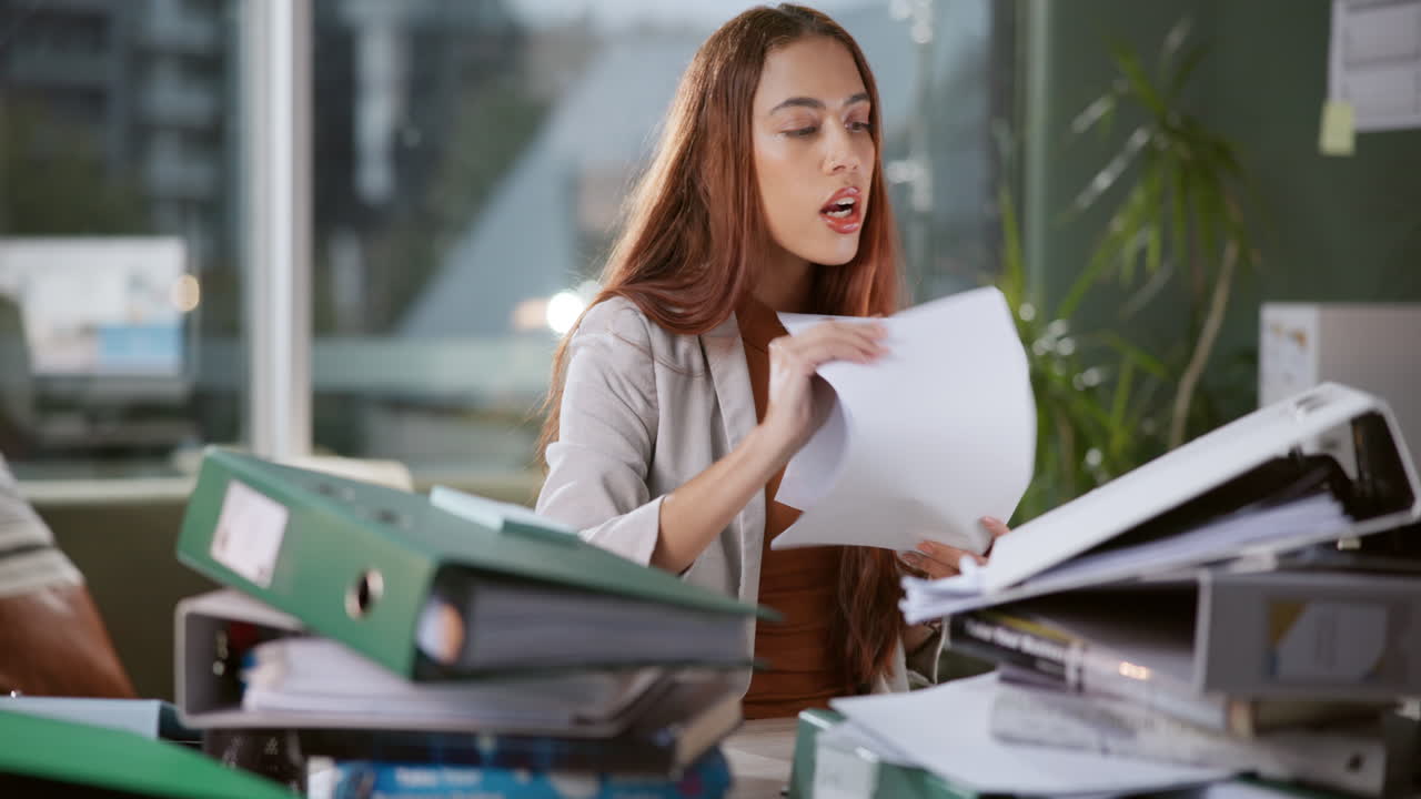 Woman overwhelmed with paperwork in office
