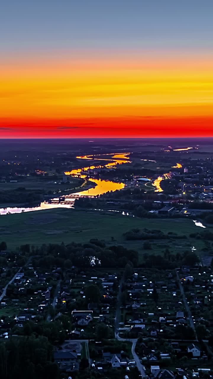 Vivid sunset over countryside with winding river and glowing horizon
