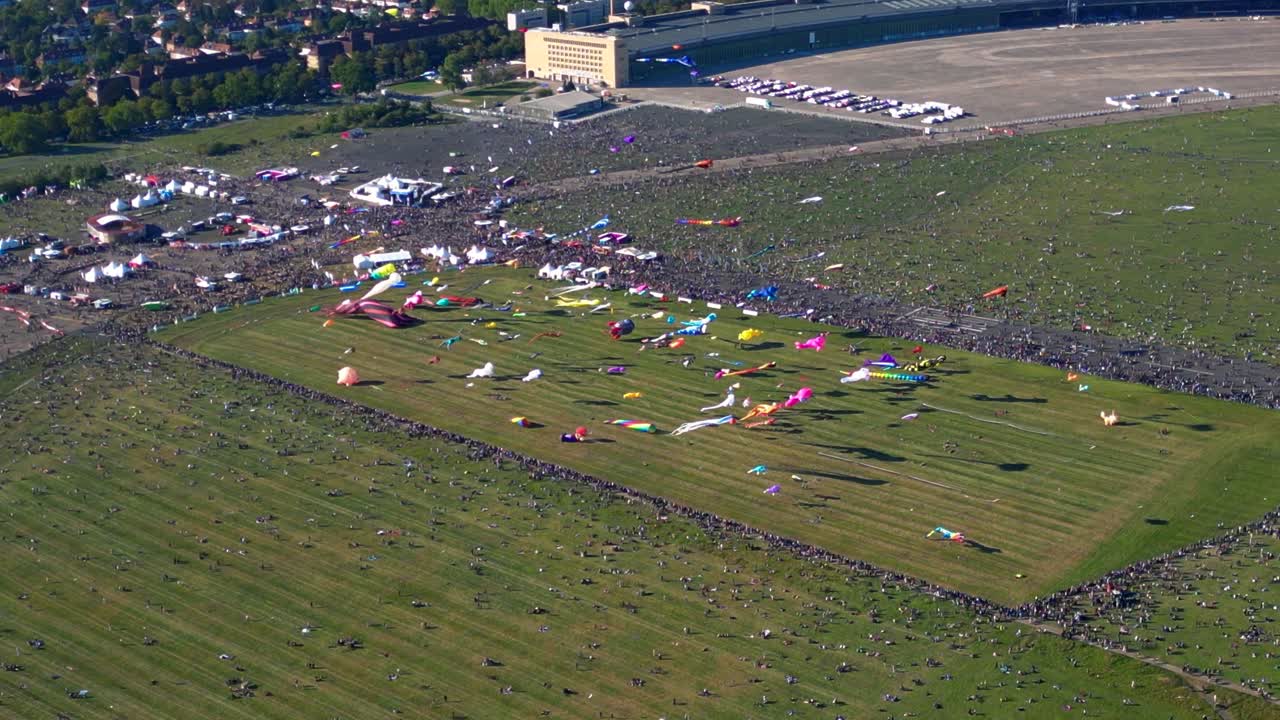 Large crowd of people gathering at the Tempelhofer Feld giant kite festival in Berlin, Germany. Tremendous aerial view flight drone shot from above