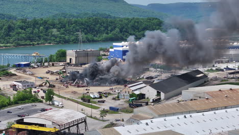 Static-aerial-footage-of-a-large-scrap-metal-fire-with-firetrucks-and-emergency-vehicles-surrounding-it